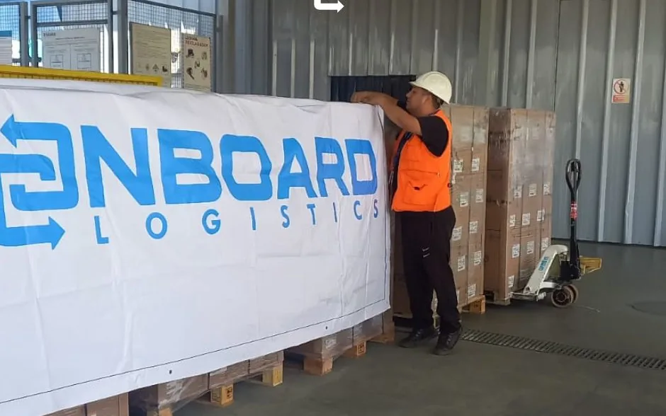 Pallets prepared for the charter flight beside the OnBoard Logistics banner