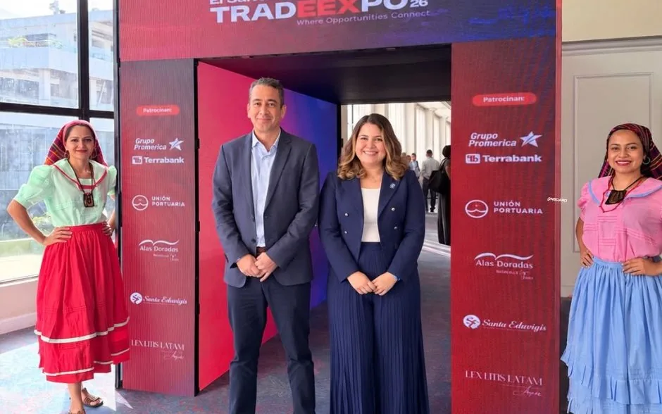 The OnBoard El Salvador team at the entrance of El Salvador TradeExpo 2026, next to two women in traditional dress