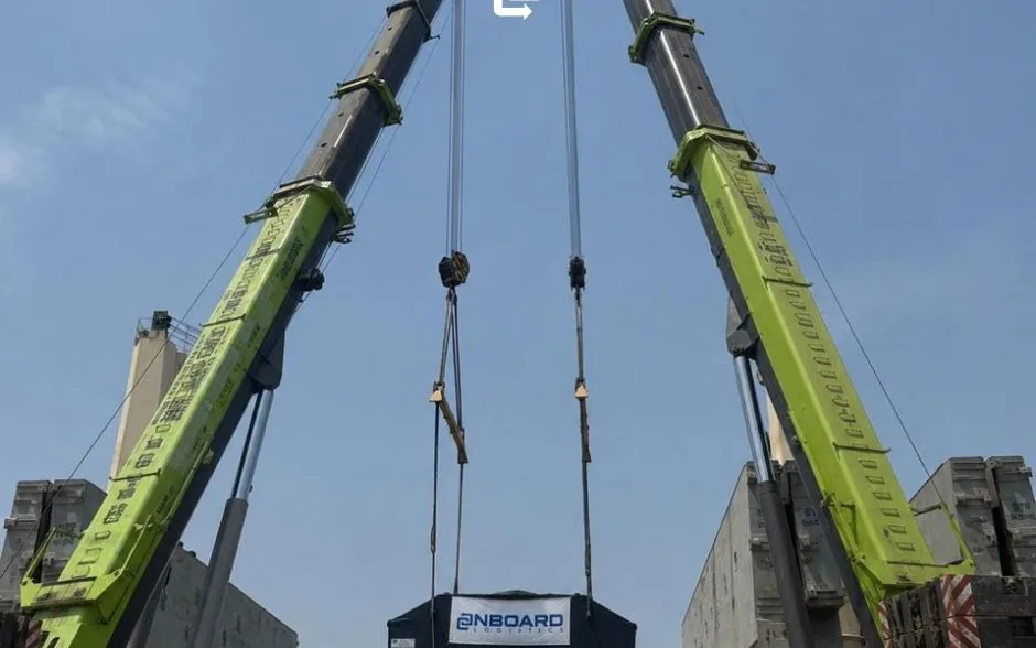 Two cranes lifting a piece of specialized cargo carrying the OnBoard banner