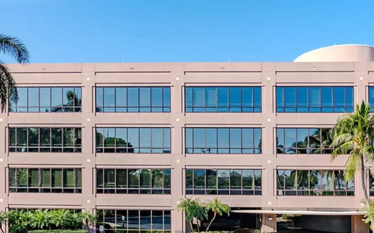 Facade of the office building of OnBoard Logistics’ new corporate headquarters in Miami, framed by palm trees