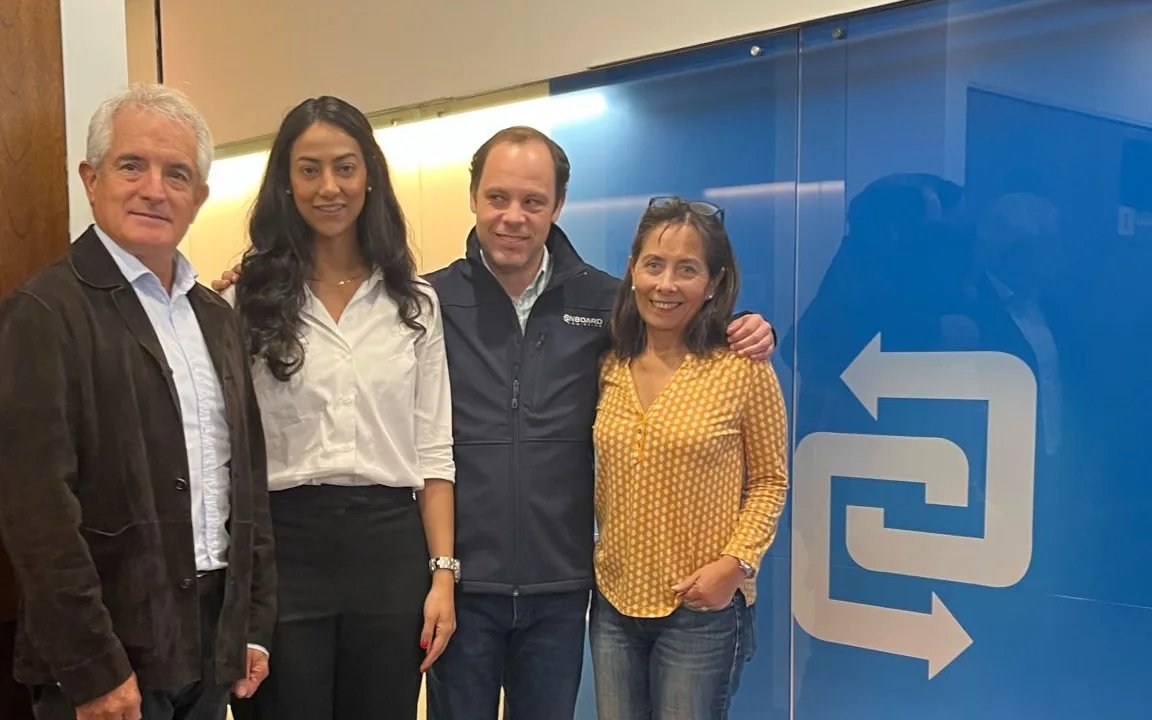 Four members of the OnBoard team at the Chile office, next to the blue wall with the brand logo