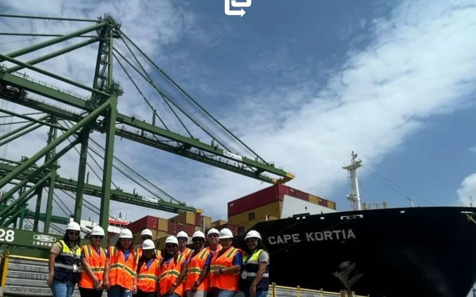 The OnBoard Panama team in hard hats and vests on the quay, beside cranes and the vessel Cape Kortia